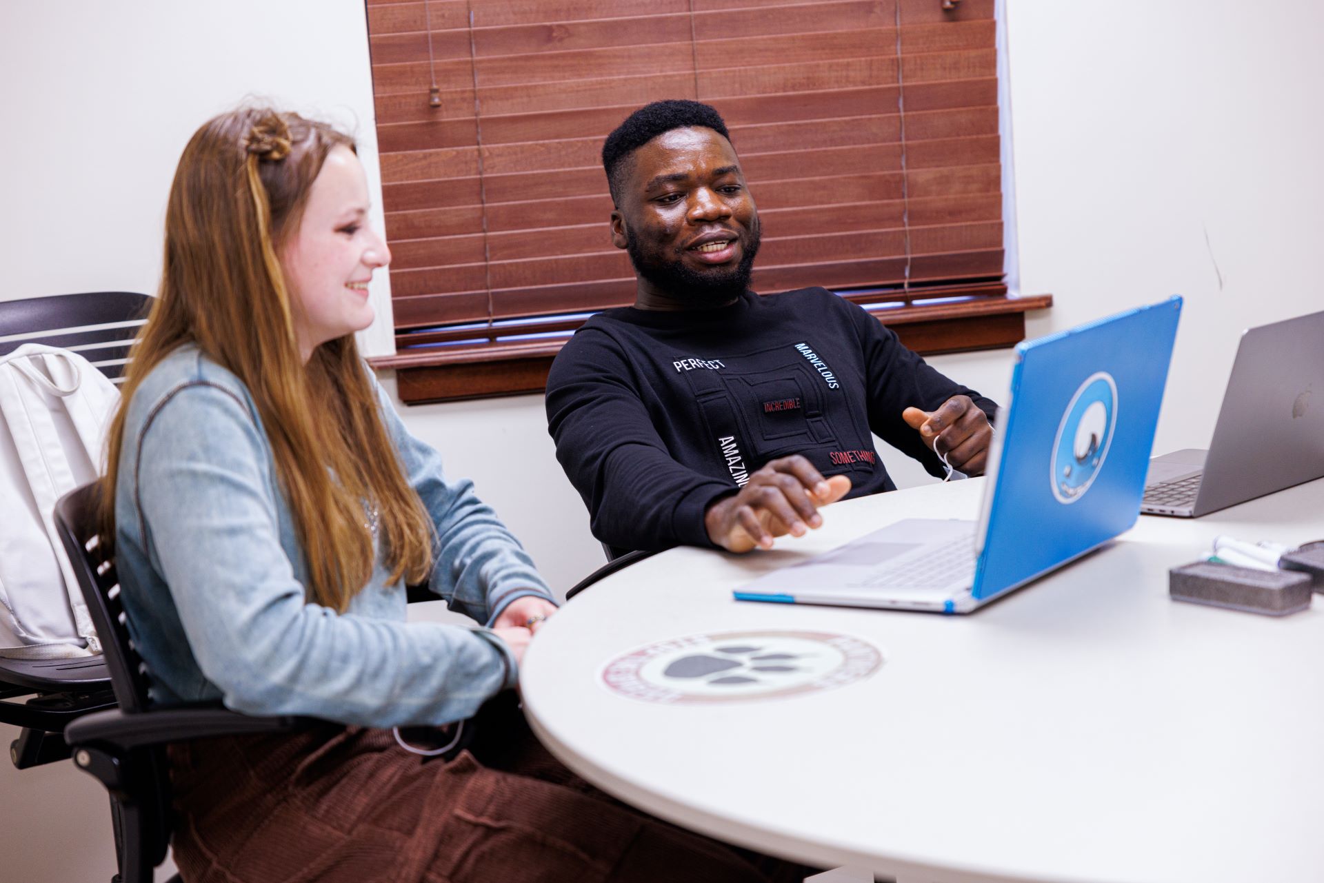 A male student and a female student looking at a computer